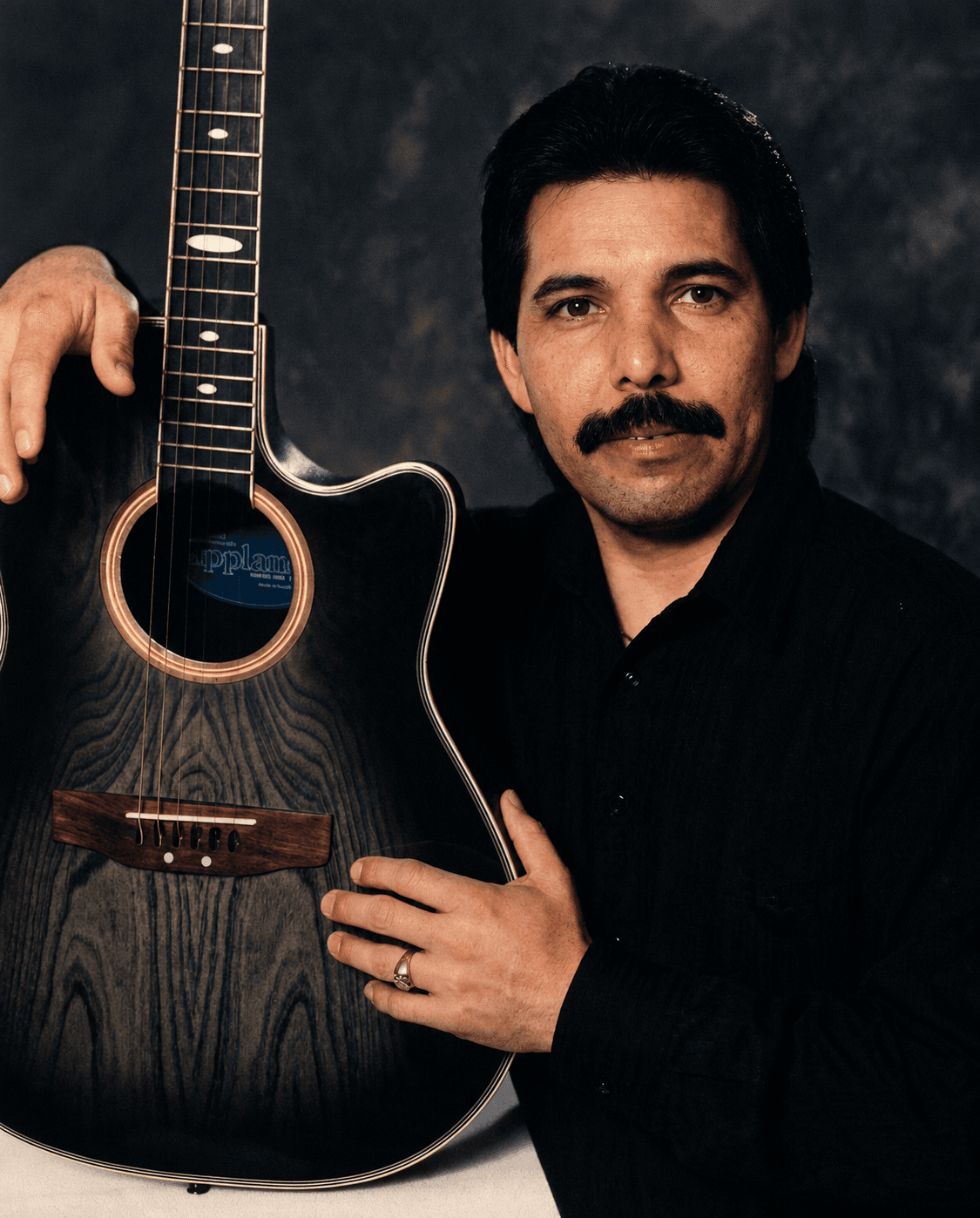 Louis Ybanez, known on stage as Lou Charles, holding an acoustic guitar